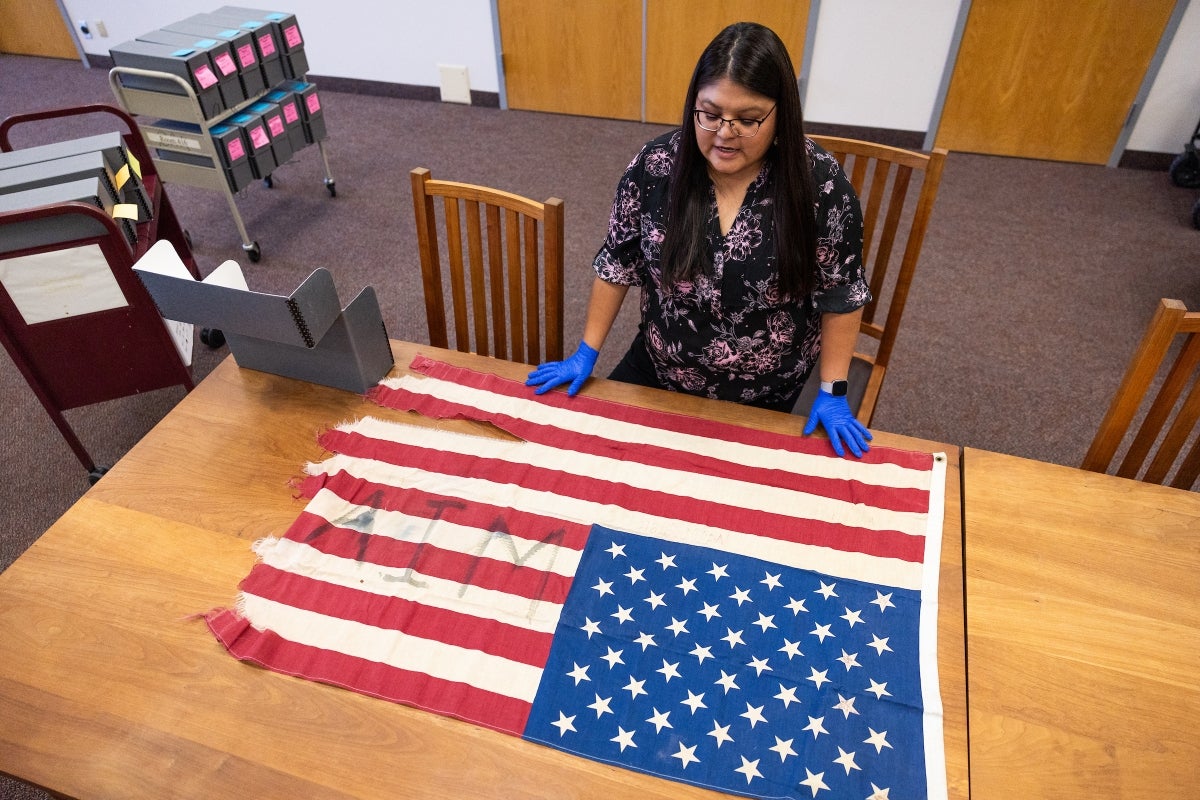 Woman with blue gloves observes a U.S. flag.