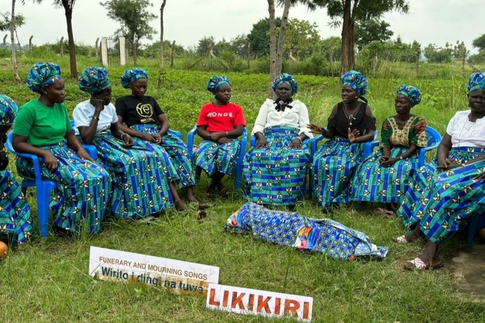 A group of women performing mourning songs in front of a corpse prop.