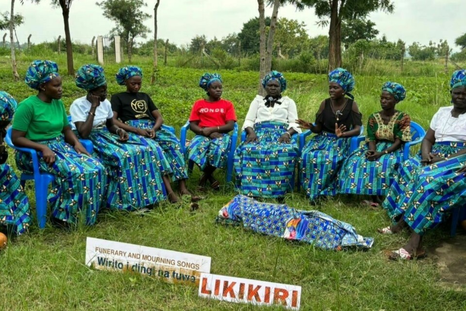 A group of women performing mourning songs in front of a corpse prop.