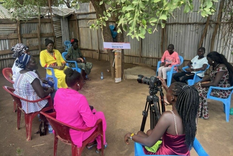 A young woman is filming an elder explaining a song in a Story Circle.