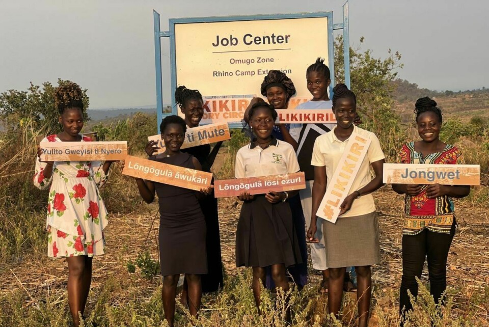 South Sudanese women in Rhino Camp holding up signs with song names.