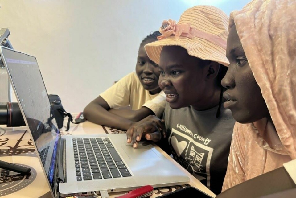 Three young women are working together on a laptop.